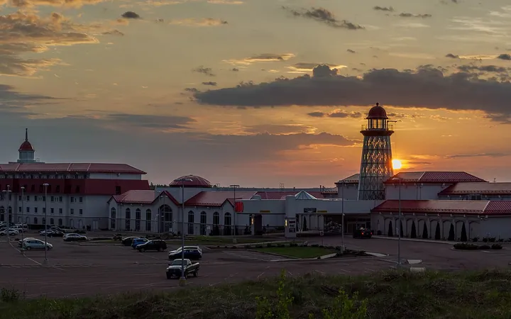 Casino Nouveau-Brunswick à Moncton au coucher du soleil : le bloc de l'hôtel, les ailes du casino aux toits rouges et la tour en forme de phare au-delà du stationnement